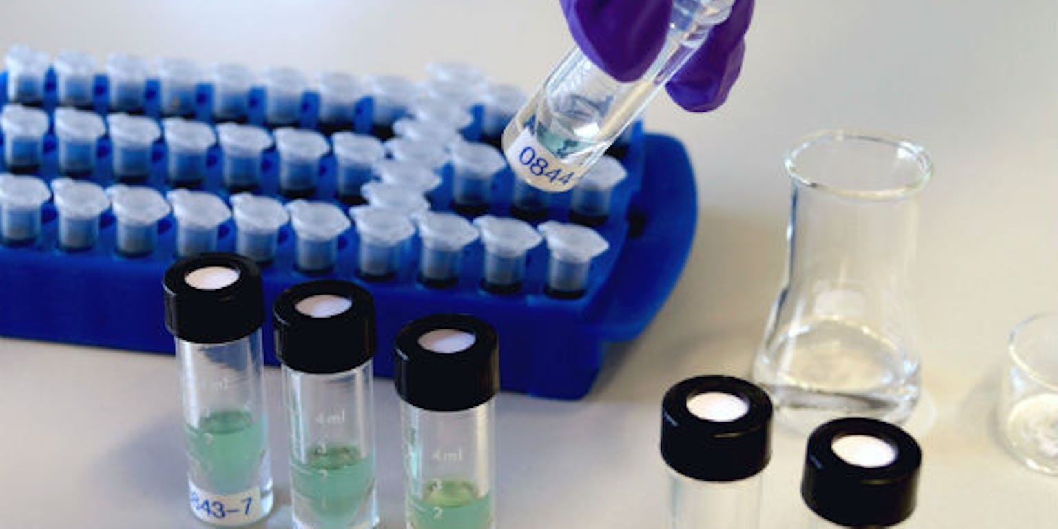 Een persoon giet vloeistof in een reageerbuis.