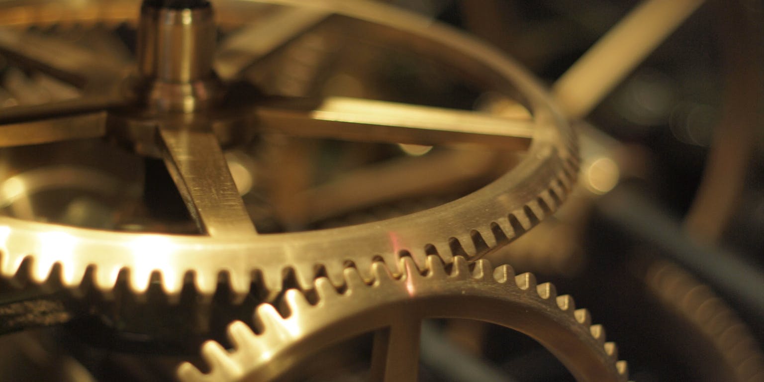 Gouden tandwielen die in elkaar draaien.