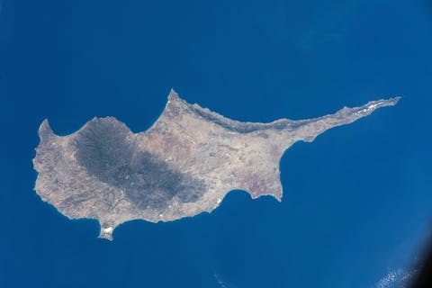 Cyprus haalt 70 procent van het drinkwater via ontzilting uit zeewater. Eiland vanaf boven gezien in blauwe zee.