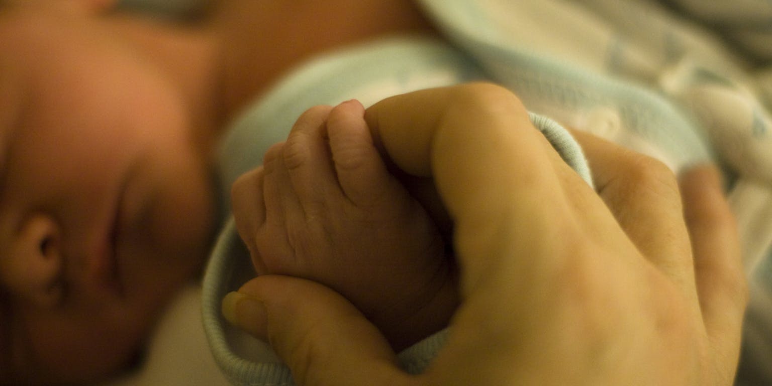 De voet van een baby wordt vastgehouden door de hand van een persoon.