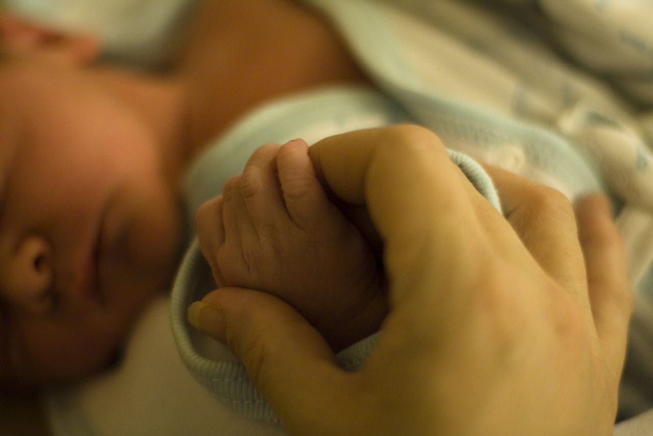De voet van een baby wordt vastgehouden door de hand van een persoon.