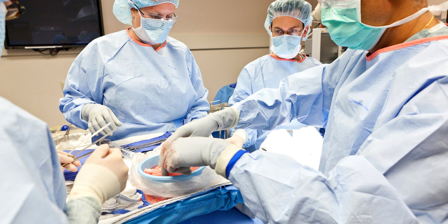 Vier mensen die een operatie uitvoeren in een operatiekamer.