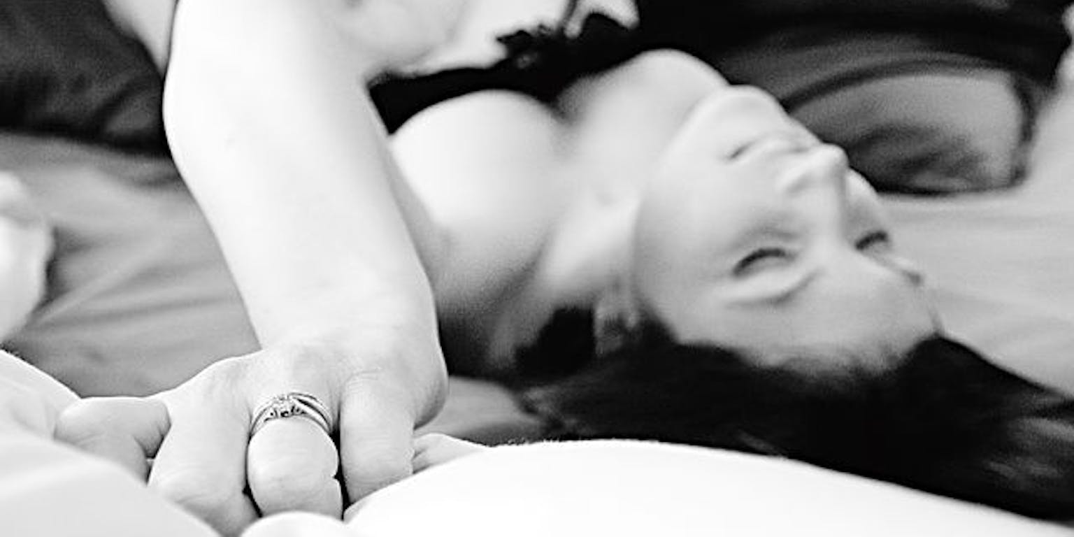 Zwart-witfoto van een vrouw die op een bed ligt in haar lingerie.