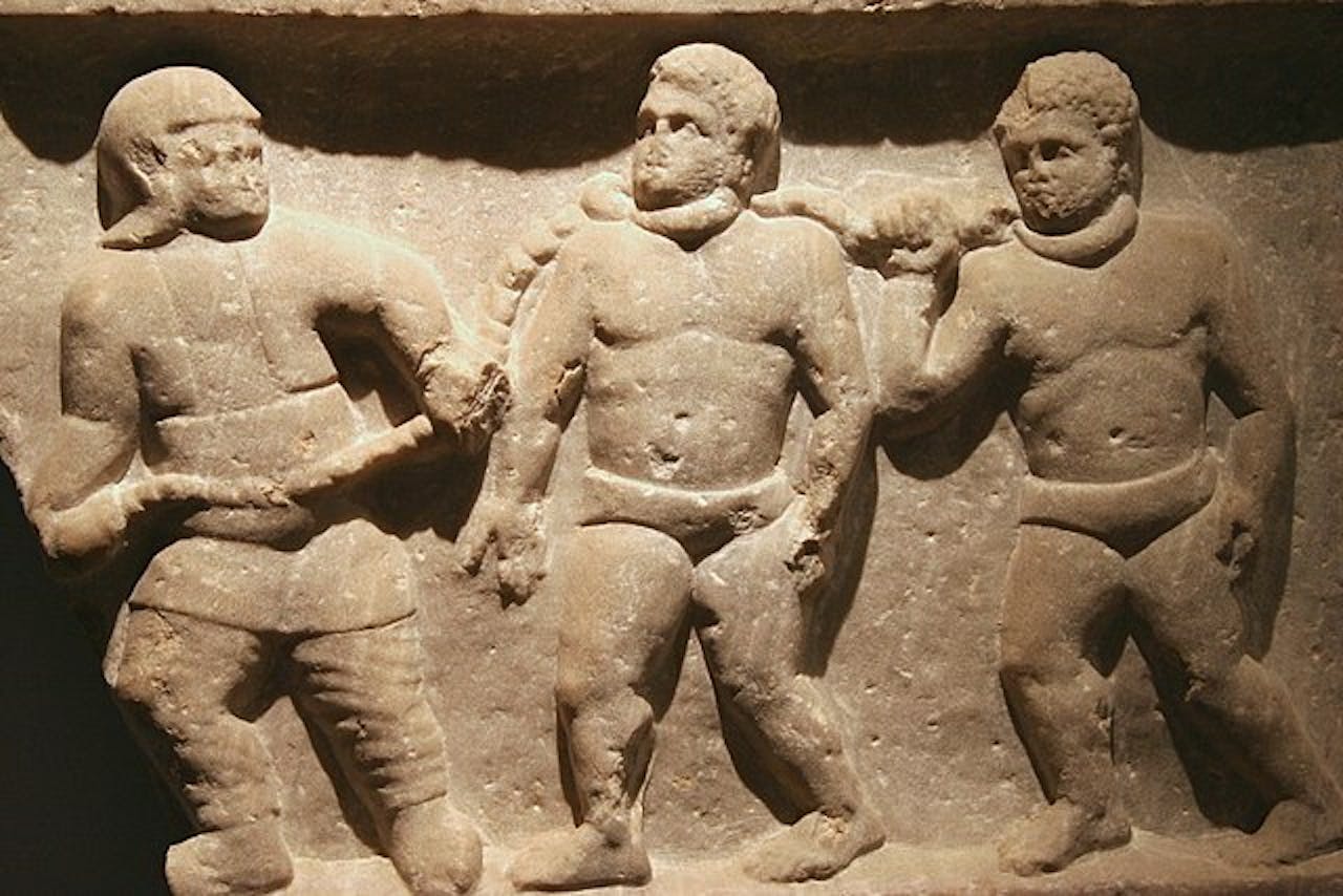 Een Romeins soldaat leidt krijgsgevangenen weg in kettingen (reliëf uit Smyrna, Izmir, Turkije. The Ashmolean Museum, Oxford, Engeland.) Op deze manier kwamen ook kinderen terecht op plekken, ver van hun geboorteplaats.