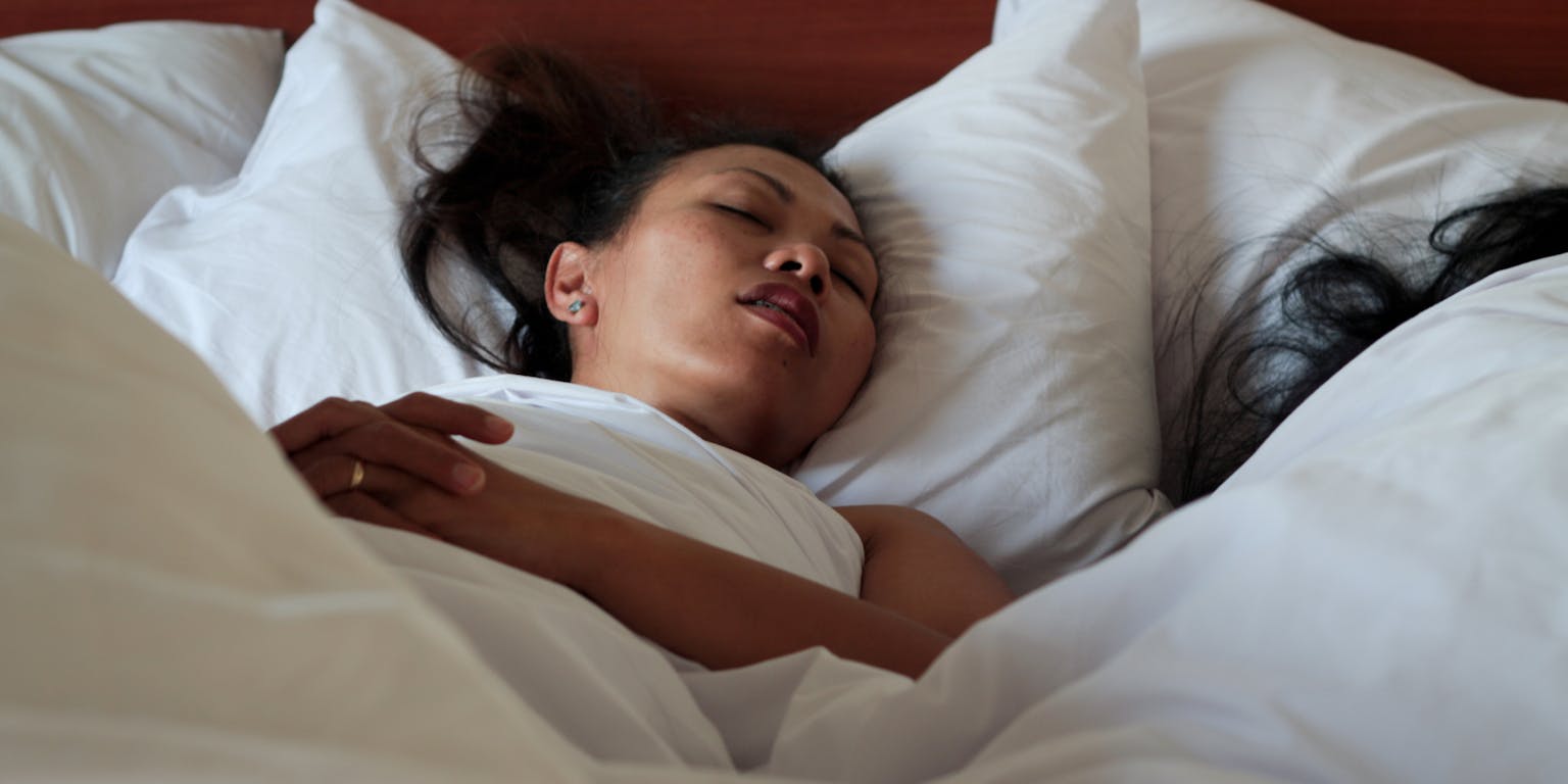 Een vrouw die in een bed slaapt.