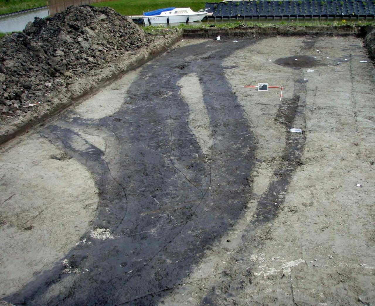 Foto van een greppelbundel op de vindplaats Enkhuizen- Kadijken uit de bronstijd (naar: Roessing & Lohof 2011, 136, afb. 4.76). “Deze greppelbundel kon over een afstand van ten minste 460 meter worden gevolgd. De bundel bestaat uit verschillende greppels die diverse malen naast elkaar gegraven zijn. De oude greppel kon dan direct met de grond uit de nieuwe greppel worden opgevuld en zo ontstonden brede bundels.”