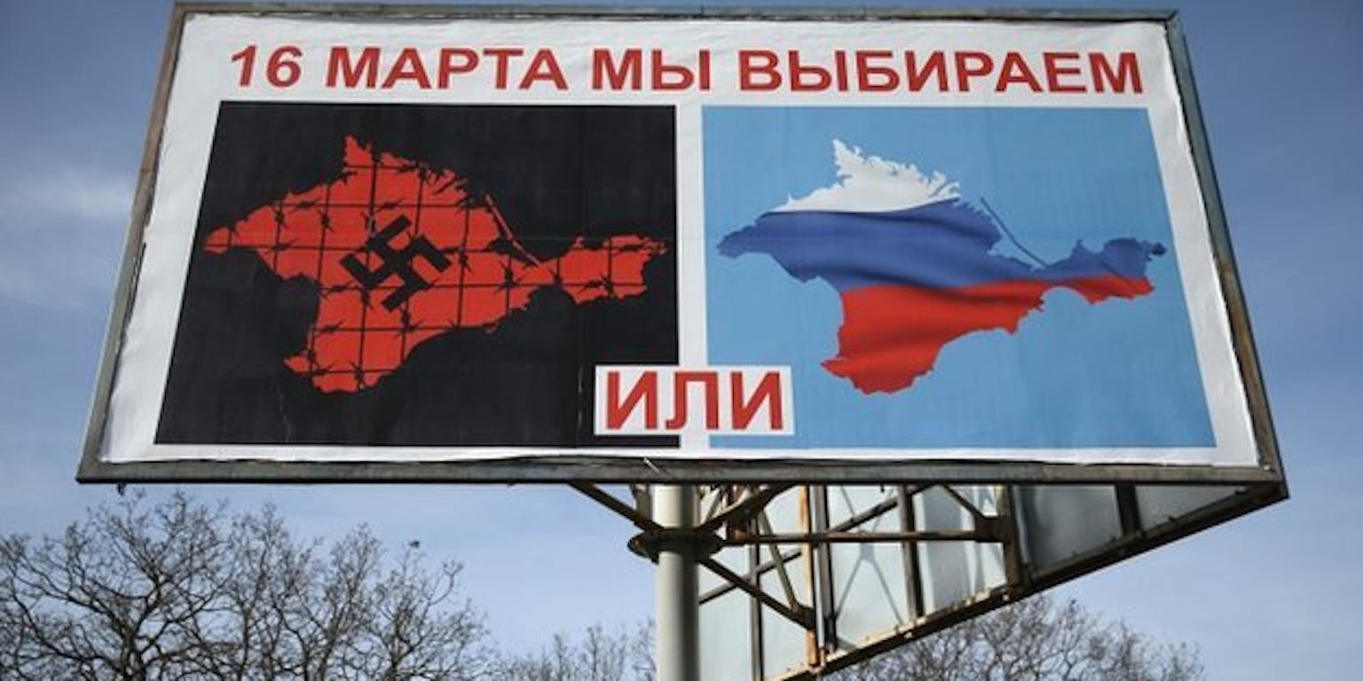 Een billboard waarop twee afbeeldingen te zien zijn. Er staat de volgende tekst: ‘Op 16 maart kiezen we’. Met links een afbeelding van de Krim onder een hakenkruis met prikkeldraad en rechts een afbeelding van de Russische vlag.