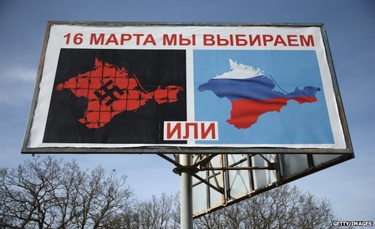 Een billboard waarop twee afbeeldingen te zien zijn. Er staat de volgende tekst: ‘Op 16 maart kiezen we’. Met links een afbeelding van de Krim onder een hakenkruis met prikkeldraad en rechts een afbeelding van de Russische vlag.
