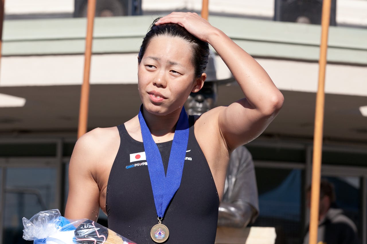 Een foto van zwemster Natsumi Hoshi. Ze draagt een medaille om haar nek.