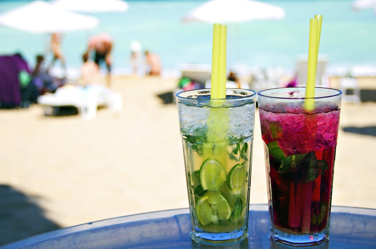 Geen drankjes op het strand,. Wantje gaat toch niet op vakantie omdat je partner op het laatste moment afzegt. Twee drankjes op een tafel op het strand.