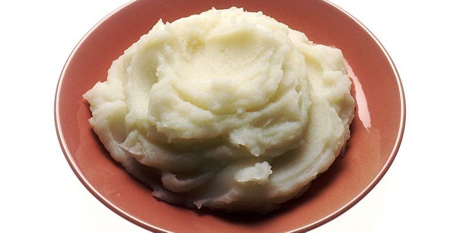 Een bruine kom aardappelpuree op een witte achtergrond.