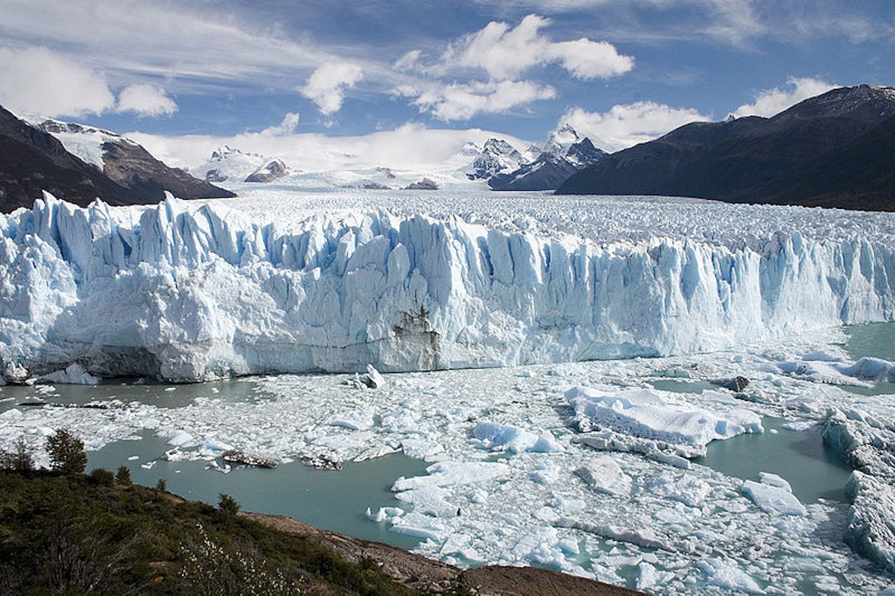 Een grote gletsjer met ijs en water op de achtergrond.