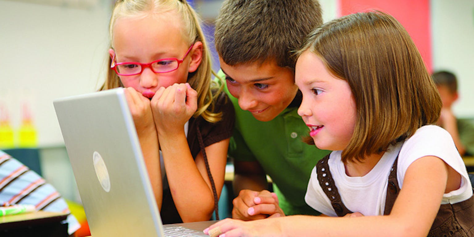 Een groep kinderen kijken naar een laptop.