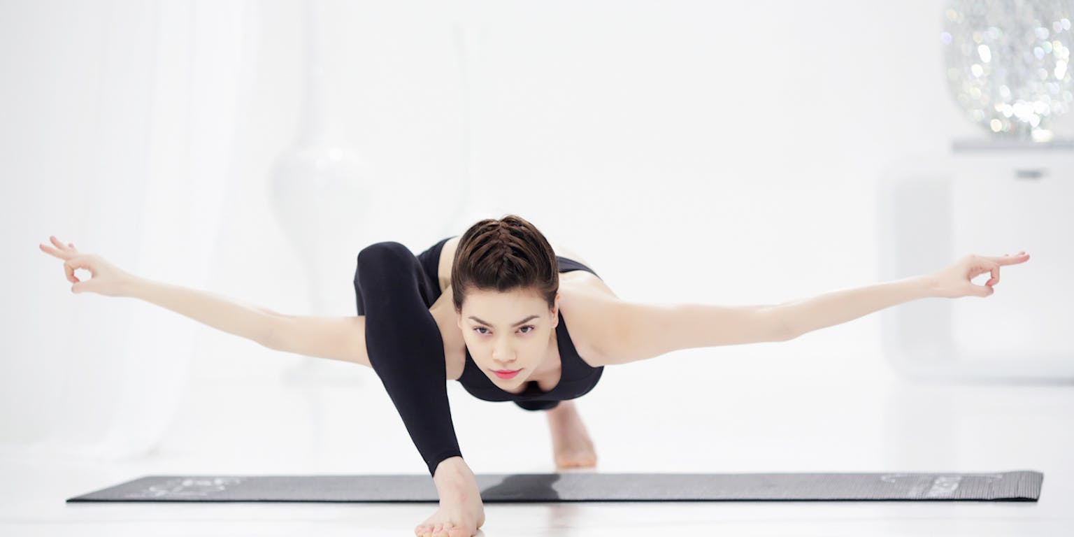 Een vrouw die een yogahouding doet op een mat.