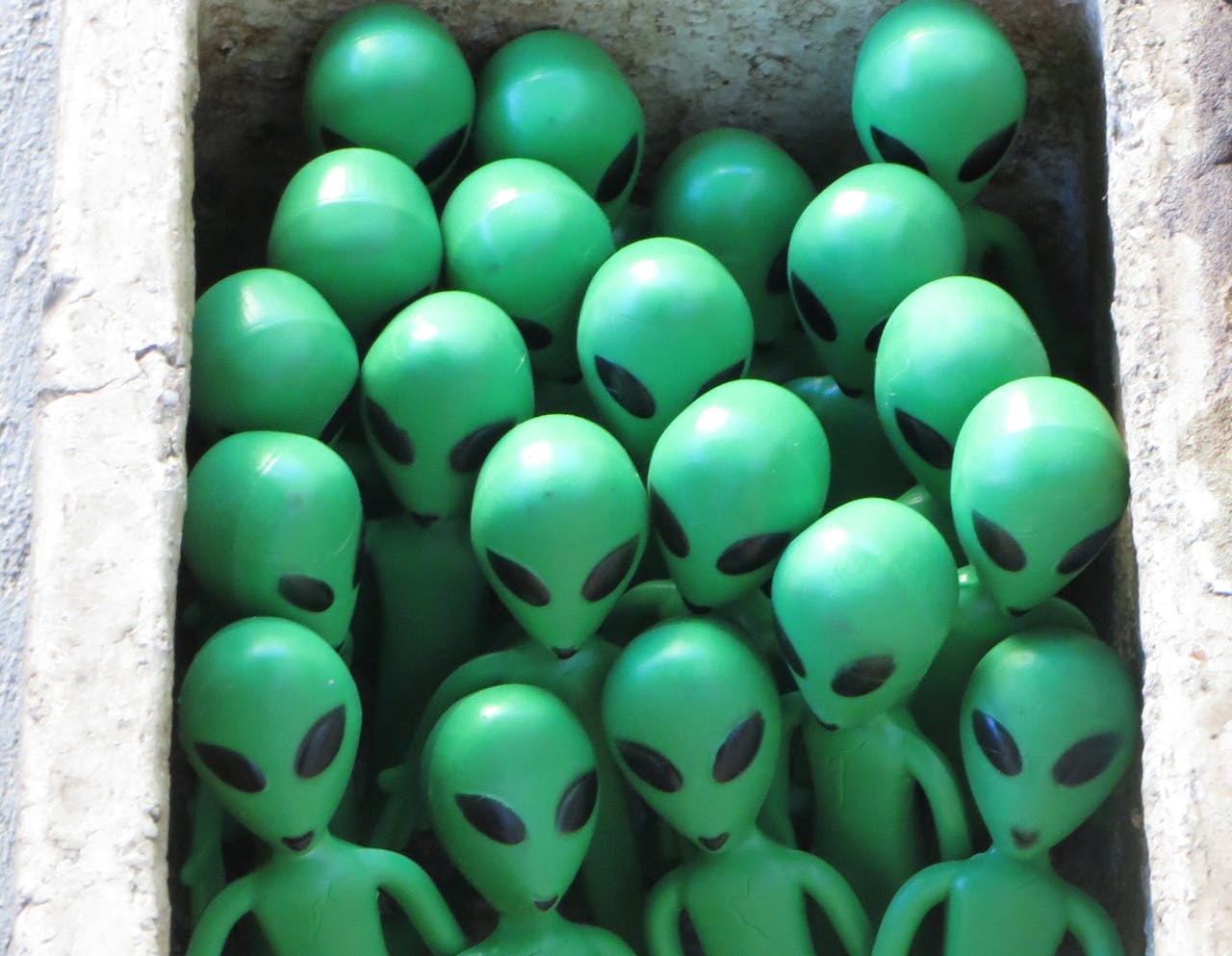Een groep groene beeldjes van buitenaardse wezens in een doos.