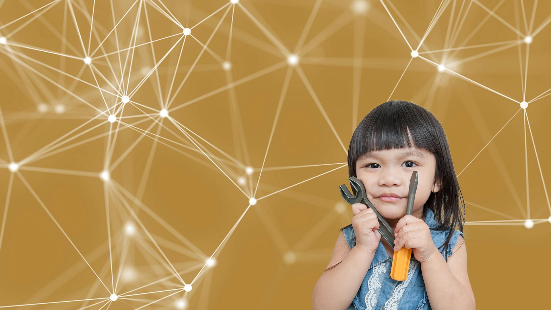 Een klein meisje met donker haar kijkt richting de camera. Ze houdt een steeksleutel en een schroevendraaier tegen haar wangen.