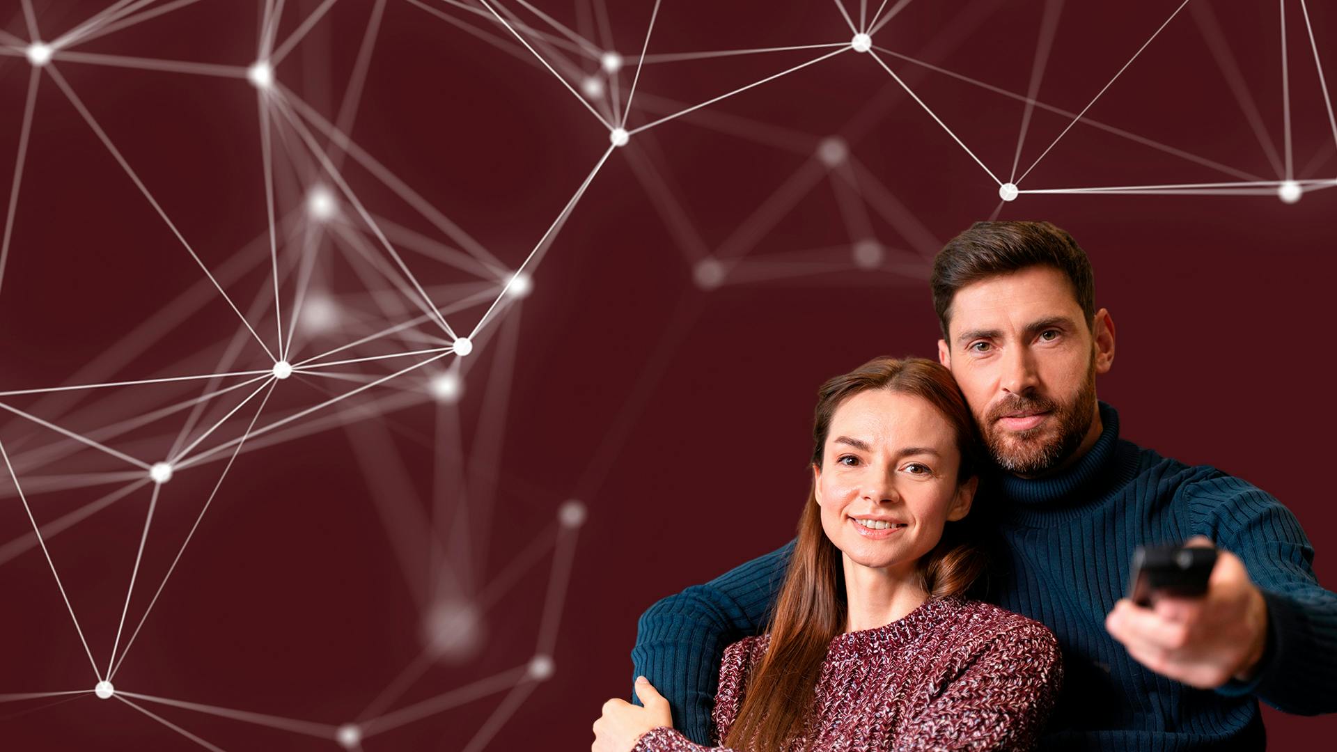 Een man en een vrouw leunen tegen elkaar aan. De man heeft een afstandsbediening in zijn linkerhand en wijst deze richting de camera.