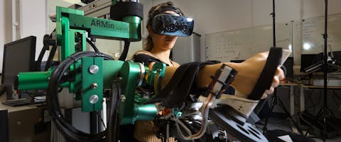 De ARMin-robotarm van de TU Delft. Een persoon met virtual reality-bril heeft haar rechterarm in de ARMin-robotarm