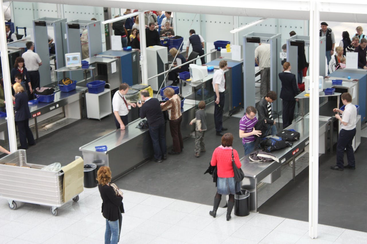 Een groep mensen staat in de wachtruimte van een luchthaven bij de tassencontrole.
