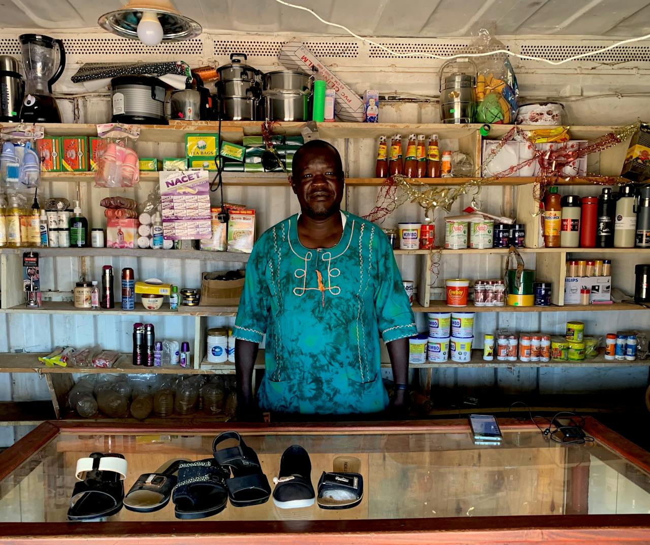 Eigenaar Alfred in zijn blauwe container (winkel) in Kalongo