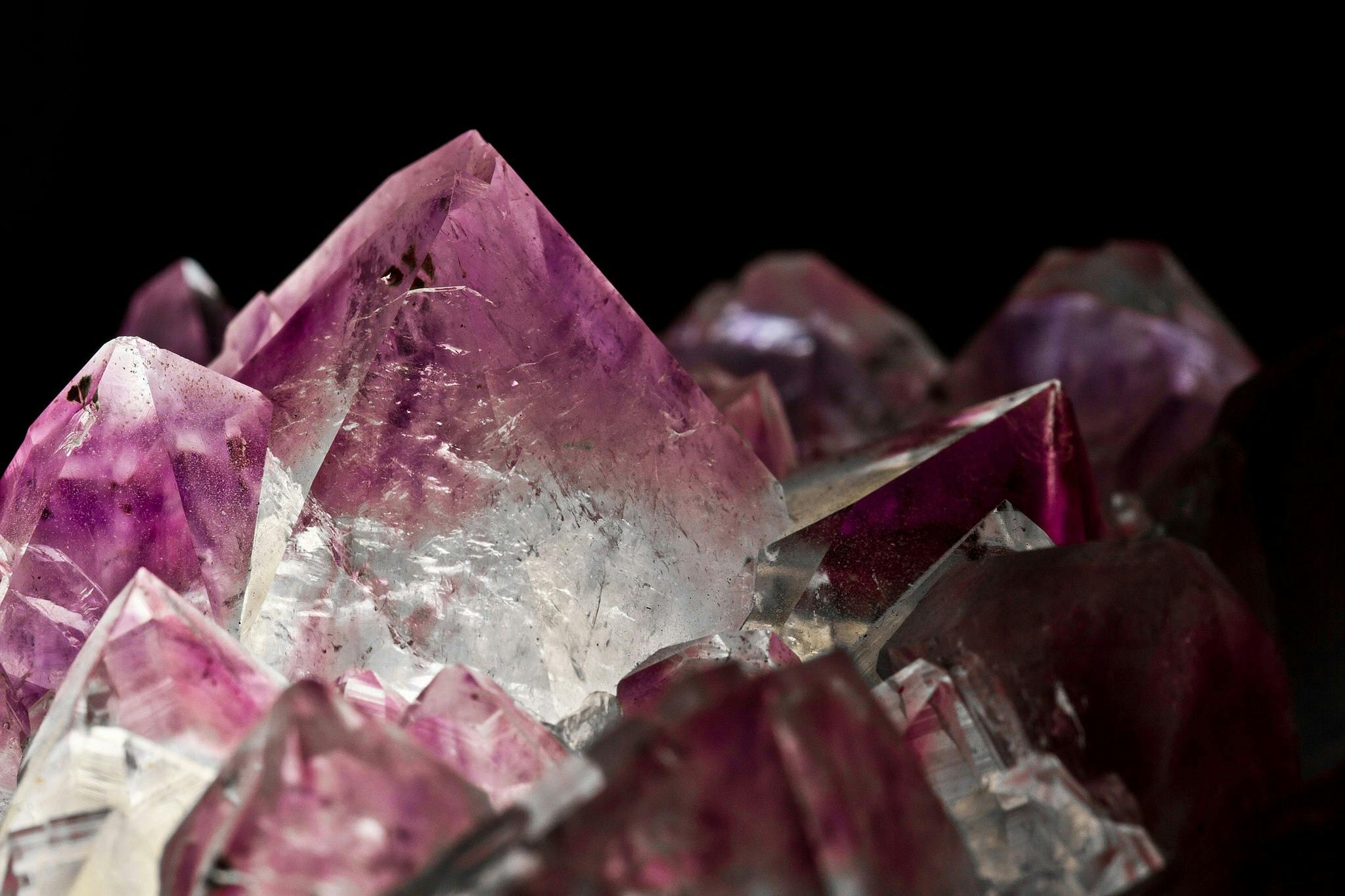Een close-up van paarse Amethyst kristallen op een zwarte achtergrond.