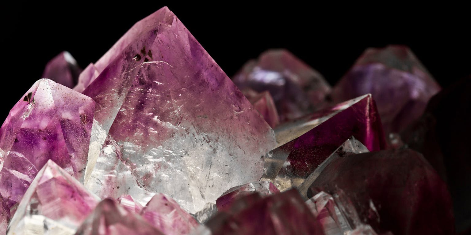 Een close-up van paarse Amethyst kristallen op een zwarte achtergrond.