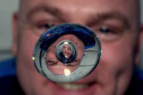De Nederlandse astronaut André Kuipers verbleef twee keer in het ISS, in 2004 en in 2011-2012.  Een wazige close-up van astronaut André Kuipers met voor zijn gezicht zwevend een waterdruppel, waarin zijn gezicht wordt weerspiegeld.