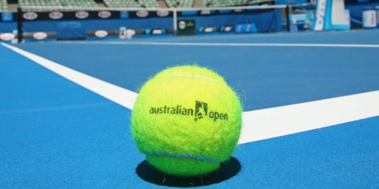 Een Australische open tennisbal ligt op een blauw veld.