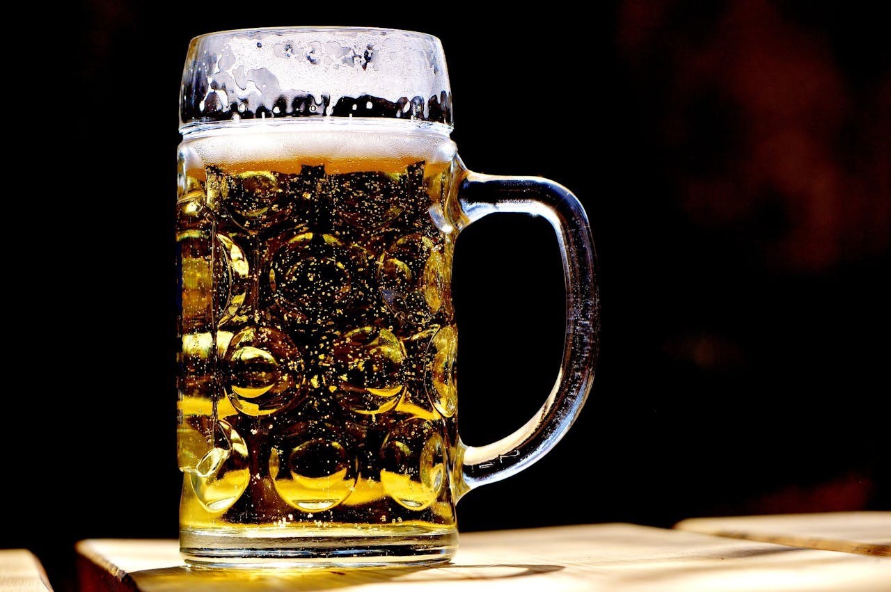 Een doodgeslagen biertje in een bierpul op een houten tafel.