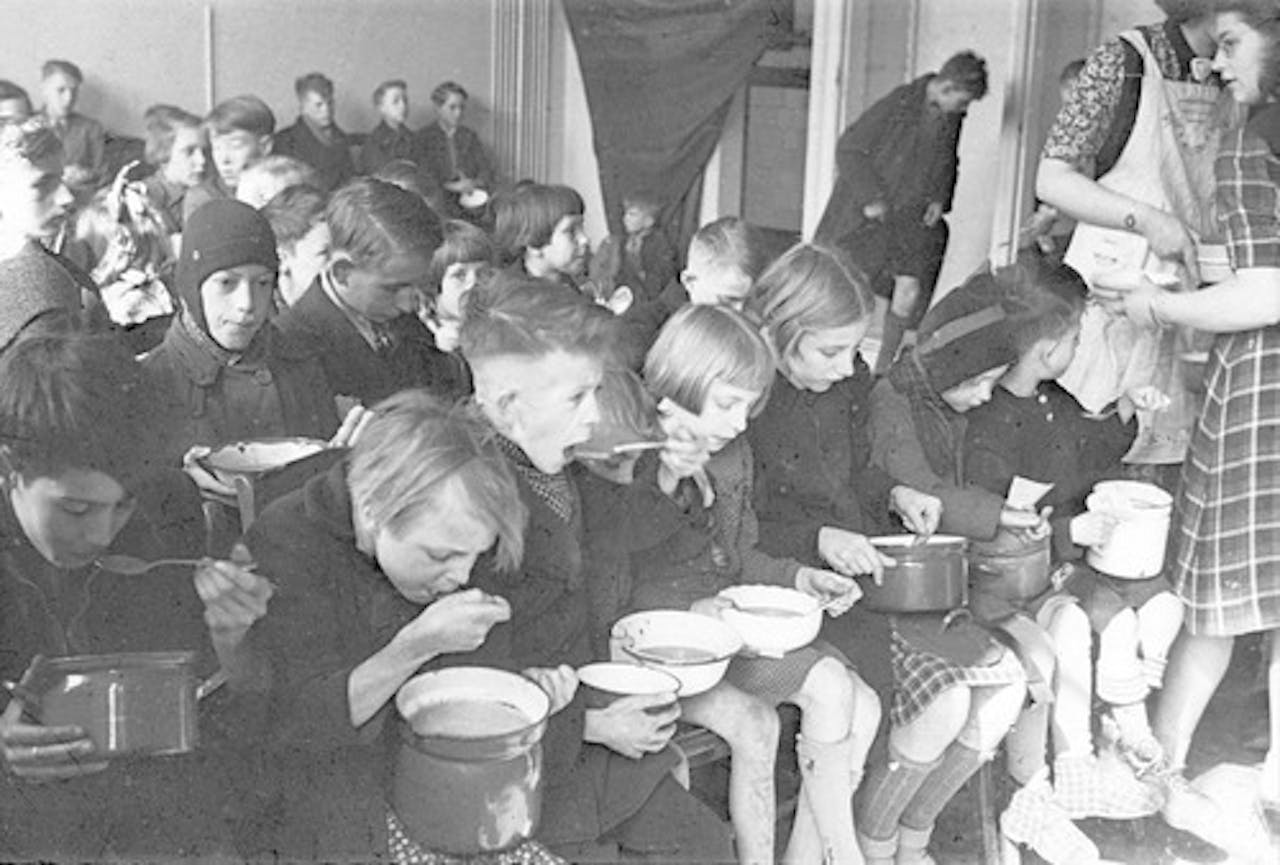 Een zwart-witfoto van een groep kinderen tijdens de 'hongerwinter' van 1944-1945. Ze krijgen extra voeding.