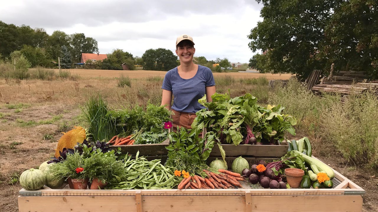 Een vrouw staat bij verschillende soorten groenten op een tafel