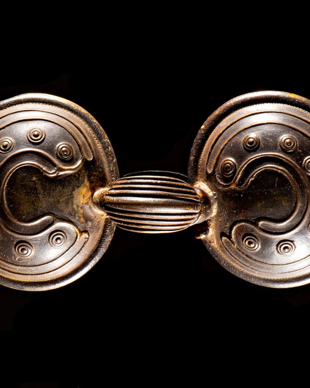 Bronzen brilfibula, sierspeld of mantelspeldBrons; breed 16 cm.; datering 1200-800 v.Chr.; gevonden inNoordwijkerhout, Zuid-Holland Bronzen brilfibula, sierspeld of mantelspeld