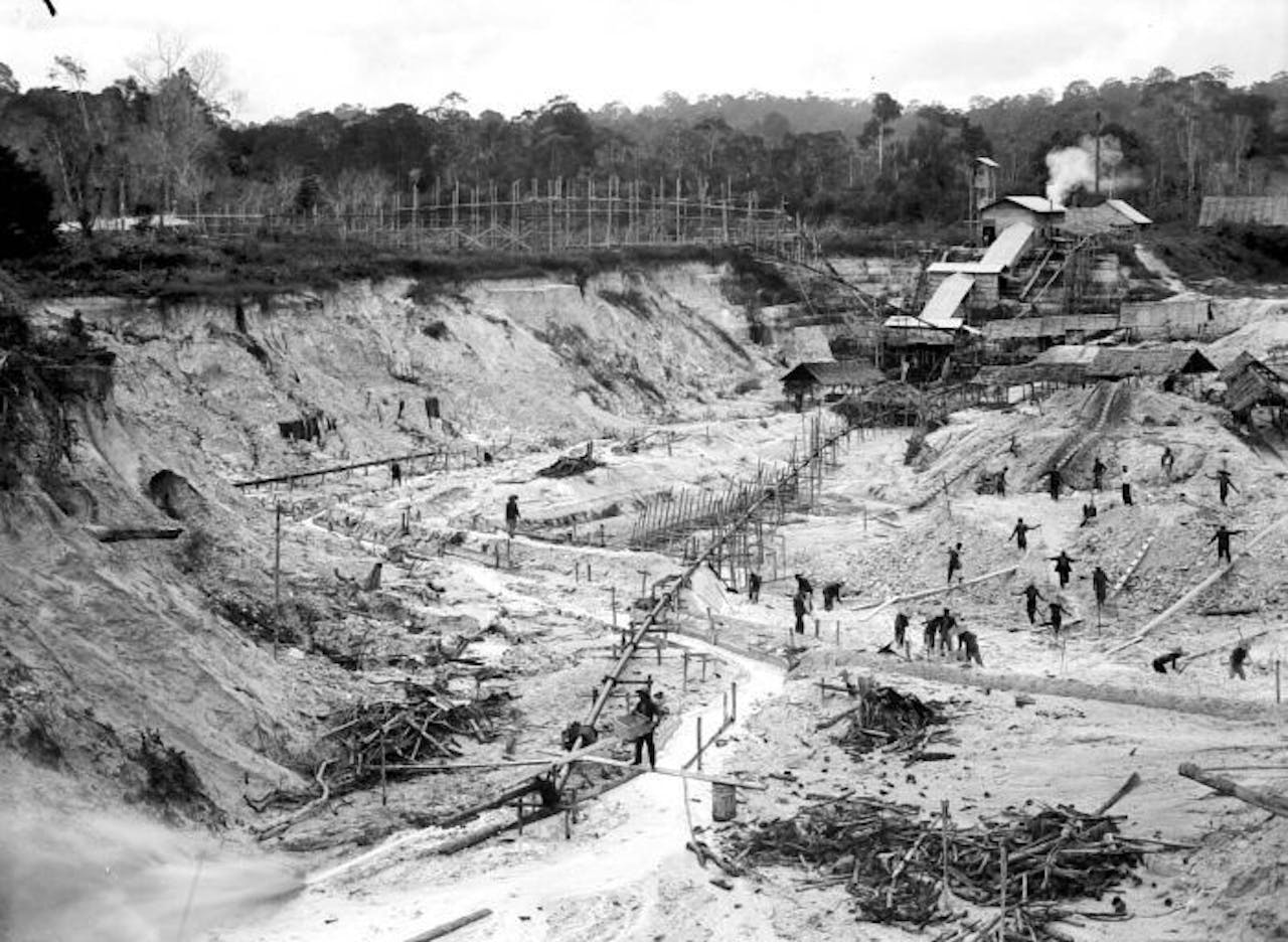 Inheemse arbeiders graven voor de Billiton Maatschappij een grondlaag met tin-erts af op Nederlands-Indië.