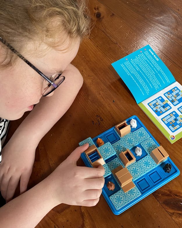 Close-up van een meisje dat een smart game speelt aan tafel. Close-up van een meisje dat een smart game speelt aan tafel.