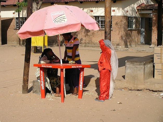 Een verkooppunt van telecommaatschappij Celtel met een rode parasol op straat in Malawi.