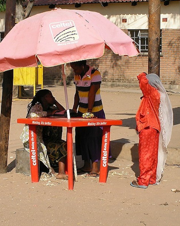 Een verkooppunt van telecommaatschappij Celtel met een rode parasol op straat in Malawi.