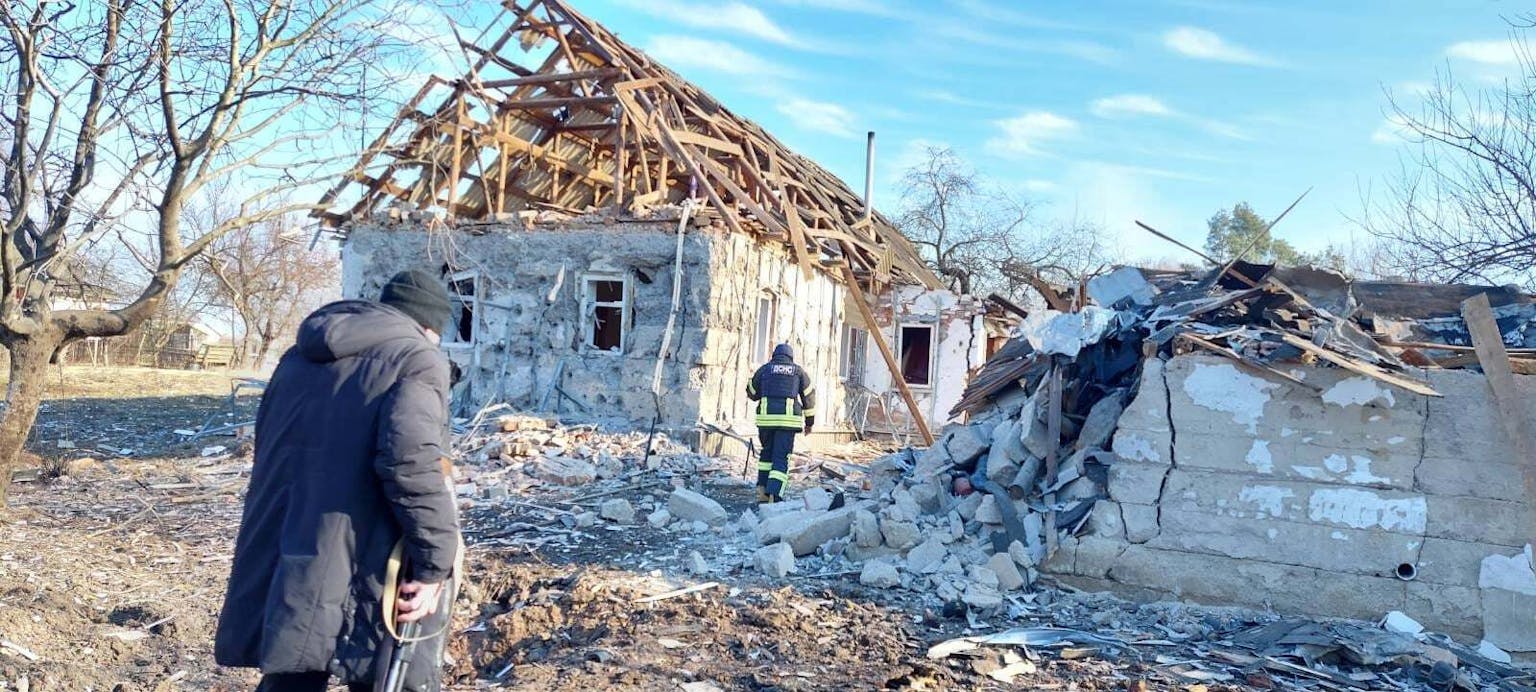 Een brandweerman staat voor een huis dat verwoest is.