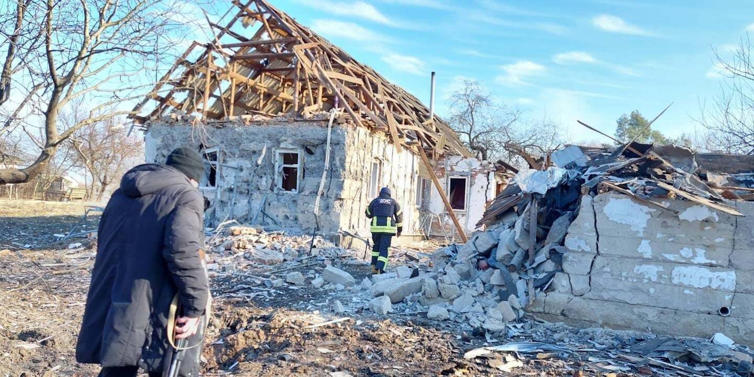 Een brandweerman staat voor een huis dat verwoest is.