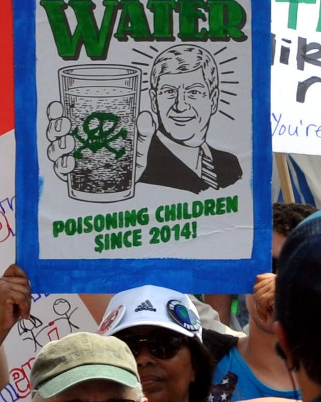 Protestbord over de watercrisis in het Amerikaanse Flint tijdens een demonstratie in 2017. Een man houdt een protestbord vast met daarop de tekst 'Flint, Michigan water. Poisoning children since 2014'.