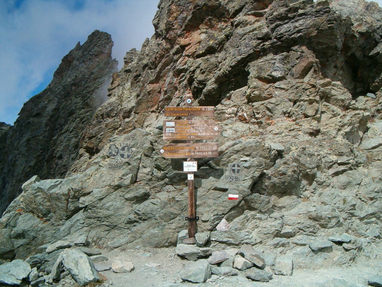 Een houten routebord aan de zijkant van een rotsachtige berg.