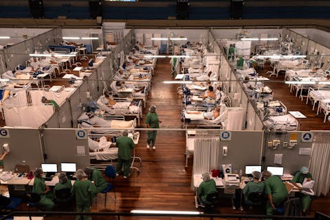 Een speerpunt van de WHO is de internationale samenwerking rond de bestrijding van infectieziektes en het voorkomen van globale pandemieën. Birds eye view van een ziekenzaal vol artsen en slachtoffers van de coronapandemie