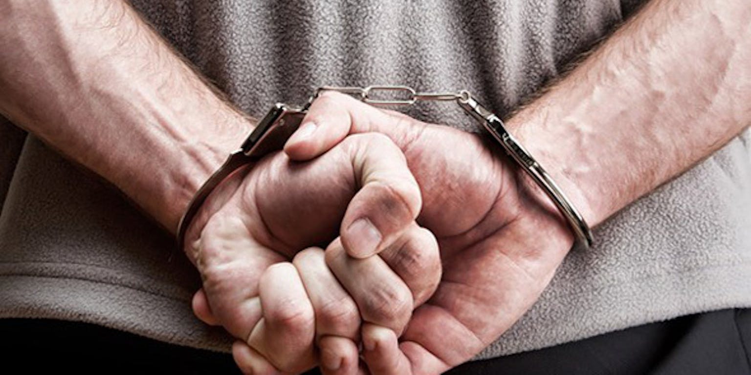 Een man met zijn handen in handboeien.