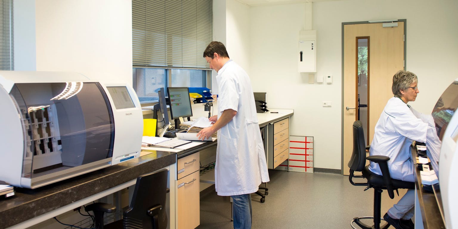 Het IntelliSite systeem van Philips en een laborantmedewerker achter een computer.