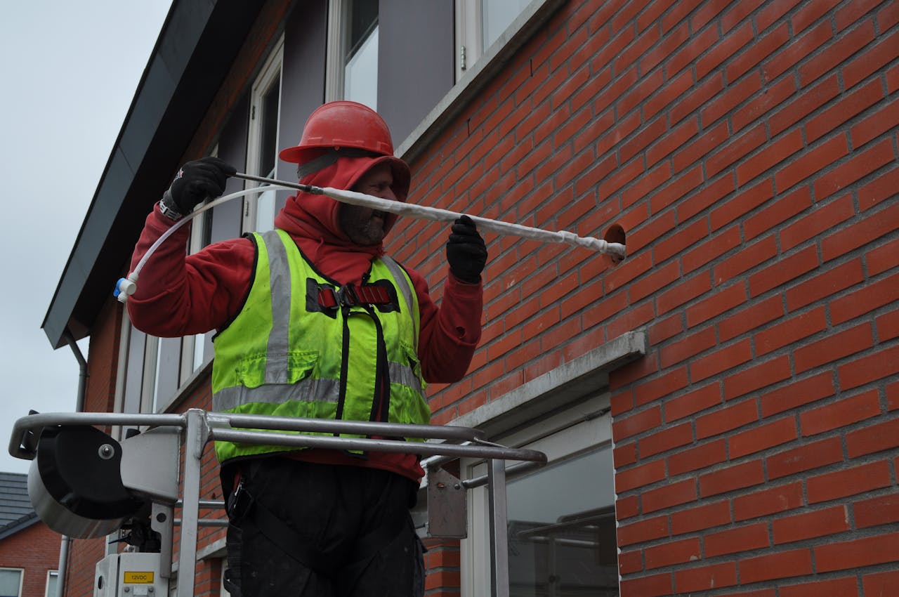 Het aanbrengen van de versteviging voor de spouwdonut in een van de acht testwoningen in Groningen.