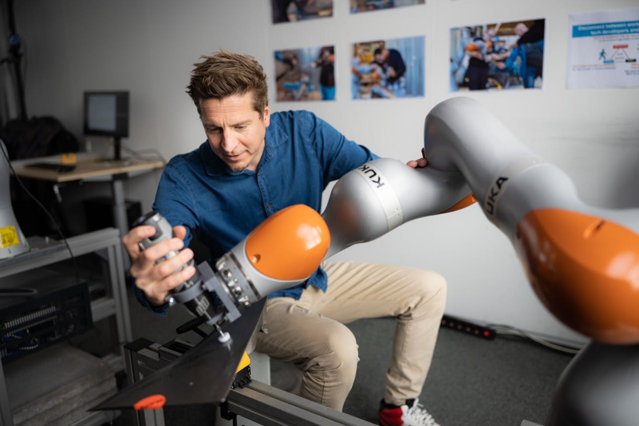 David Abbink, hoogleraar Haptische Mens-Robotinteractie aan de TU Delft, stelt aan een grote robotarm in.