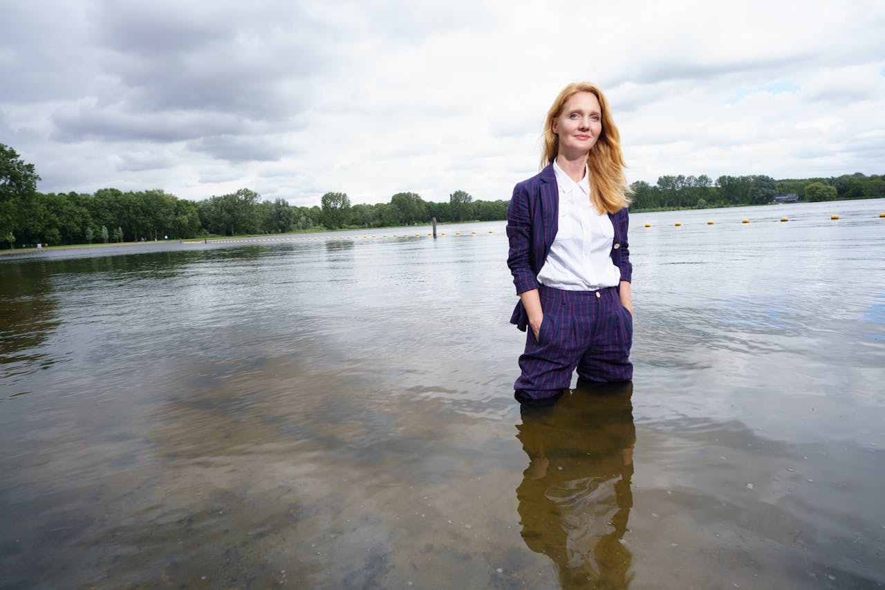 Een vrouw staat met haar kleren aan tot haar knieën in een meer.