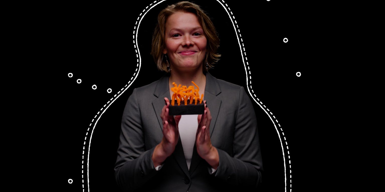 Een vrouw in een pak die een doosje met oranje uitsteeksels vasthoudt.