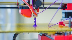 Een 3D-printer met een paarse draad eraan.