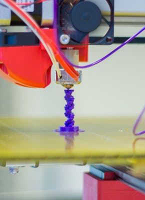 Een 3D-printer met een paarse draad eraan.