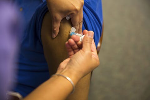 Iemand krijgt een vaccin tegen de griep in zijn arm gespoten.